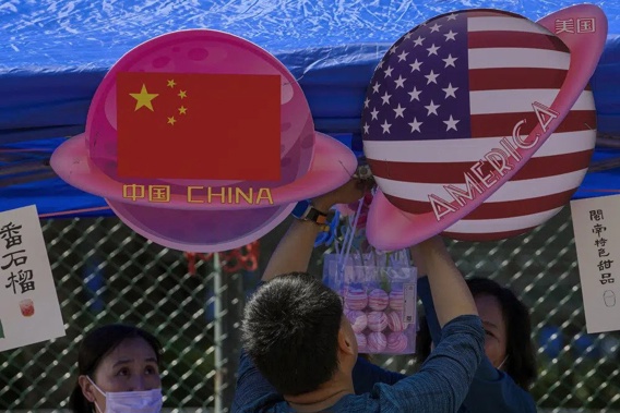 A vendor sets up foods and beverages at a booth displaying China and American flags during a Spring Carnival in Beijing, on May 13, 2023. China sentenced a 78-year-old United States citizen to life in prison Monday May 15, 2023 on spying charges, in a case that could exacerbate the deterioration in ties between Beijing and Washington over recent years. (AP Photo/Andy Wong, File)