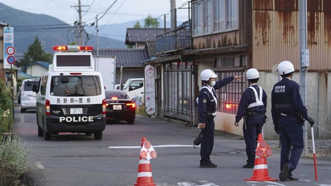 Police officers stand guard where at least three people including two police officers were killed in Nakano, a city in Nagano prefecture. Photo / via AP