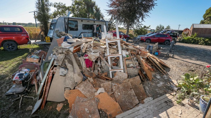 Pam and John Trotter watch over their Twyford property from their caravan in the front yard while they are removing flood damaged household items. Photo / Paul Taylor
