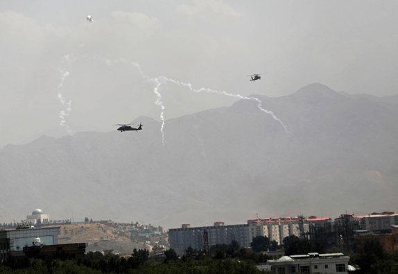 Anti-missile decoy flares are deployed as US Black Hawk military helicopters and a dirigible balloon fly over the city of Kabul. (Photo / AP)
