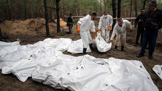 Experts work during the exhumation of bodies in the recently retaken area of Izium, Ukraine on Friday. Ukrainian authorities discovered a mass burial site near the recaptured city of Izium. Photo / AP