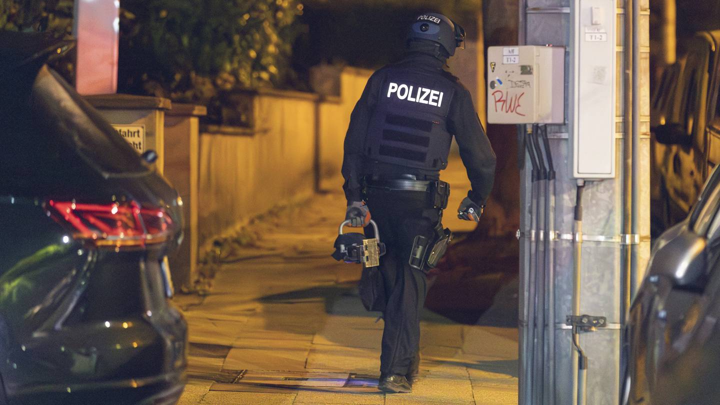 A police officer wears a hydraulic door opener walks on duty in Essen, Germany yesterday. The German Government yesterday banned a far-right, racist group known for its indoctrination of children as police raided dozens of homes of its members and other buildings early in the morning. Photo / AP