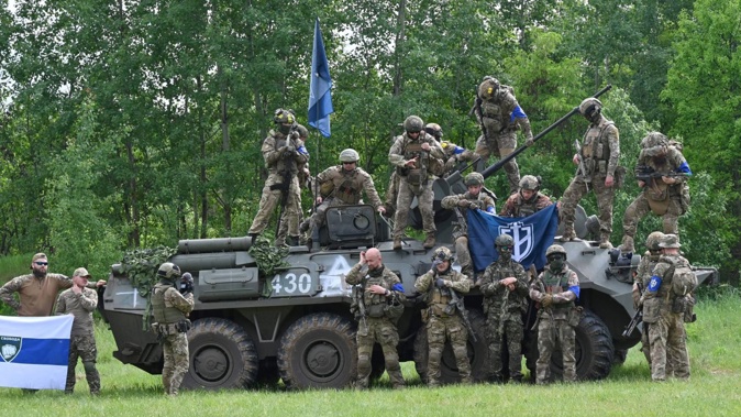 Fighters of the Russian Volunteer Corps and allied group, the Freedom of Russia Legion, stand next to a seized armoured personnel carrier on May 24, 2023. Sergey Bobok/AFP/Getty Images