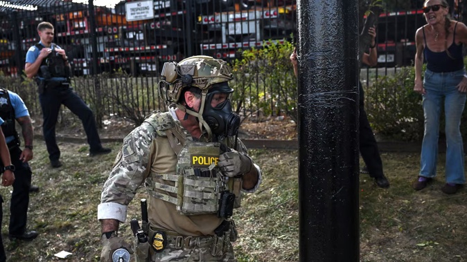 A US Customs and Border Protection agent holds a cannister as demonstrators protest along Kedzie Avenue in Chicago yesterday. Photo / Joshua Lott, The Washington Post