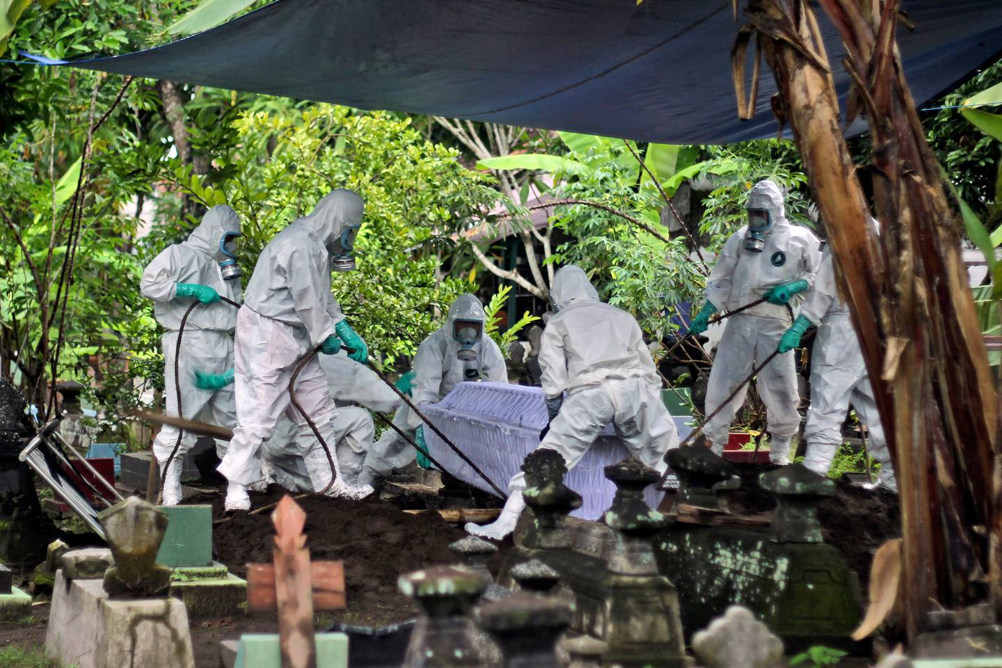 Workers in protective gear bury a coronavirus victim during a funeral at a cemetery in Yogyakarta, Indonesia. (Photo / AP)