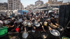 Palestinians carrying pans, gather to receive hot meals, distributed by a charity organization in Gaza City, where residents are struggling to access food due to the ongoing Israeli blockade and attacks in Gaza City, Gaza on July 23, 2025. (Photo by Khames Alrefi/Anadolu via Getty Images)
