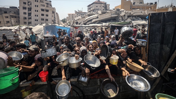 Palestinians carrying pans, gather to receive hot meals, distributed by a charity organization in Gaza City, where residents are struggling to access food due to the ongoing Israeli blockade and attacks in Gaza City, Gaza on July 23, 2025. (Photo by Khames Alrefi/Anadolu via Getty Images)