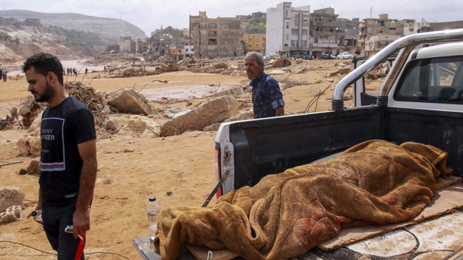 People walk past the body of a flash flood victim in the back of a pickup truck in Derna, eastern Libya, on Monday. AFP/Getty Images