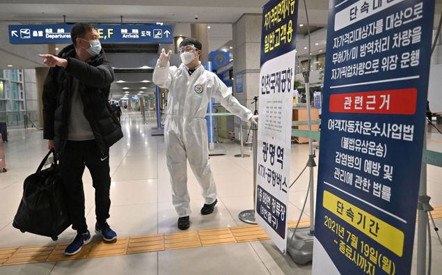 Global stocks and oil prices are falling again after a brief respite from the heavy sell-off triggered by Omicron as a staff member wearing protective equipment guides a traveller at the arrival hall of Incheon International Airport in South Korea. (Photo / Getty Images)