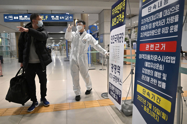 Global stocks and oil prices are falling again after a brief respite from the heavy sell-off triggered by Omicron as a staff member wearing protective equipment guides a traveller at the arrival hall of Incheon International Airport in South Korea. (Photo / Getty Images)