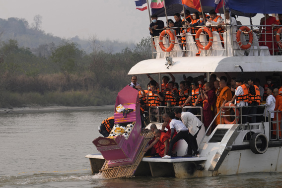 Family members, accompanied by monks and fellow mourners, release the ashes of Duangphet Phromthep in a makeshift boat along with soccer balls and some of his prized possessions into the Mekong River. Photo / AP