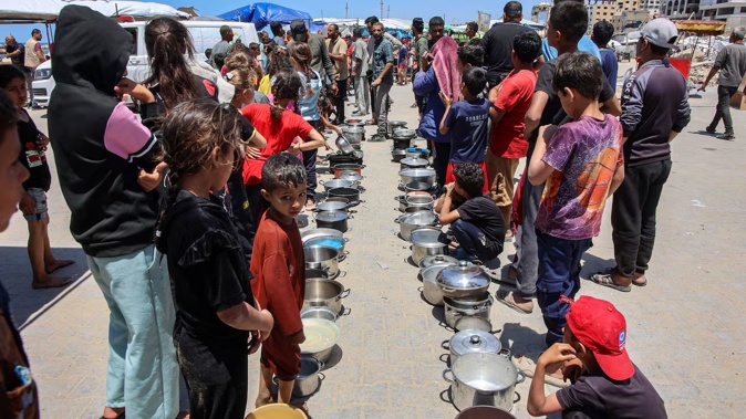 Palestinians line up to receive meals at a distribution point in the Al-Rimal neighbourhood in Gaza City after Israel said it let in dozens of UN trucks. Photo / AFP