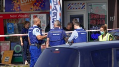 Police assist a woman after a stabbing at a New Windsor dairy in Auckland. Photo / Hayden Woodward