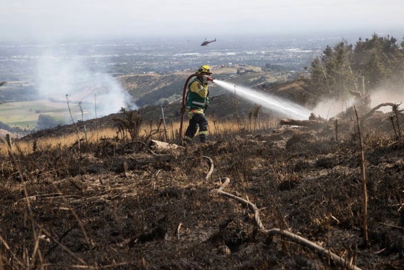Fire crews fighting the Port Hills fire are scaling back work, with all helicopters and aircraft grounded. Photo / George Heard