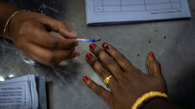 A polling official puts indelible ink mark on the index finger of a woman as she arrives to vote during the first round of voting of India’s national election in Chennai, southern Tamil Nadu state on April 19. Photo / AP