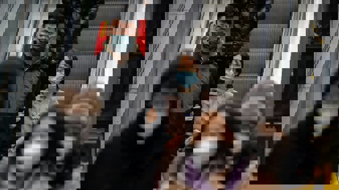 People wearing face masks ride an escalator at a shopping and office complex in Beijing. Photo / AP