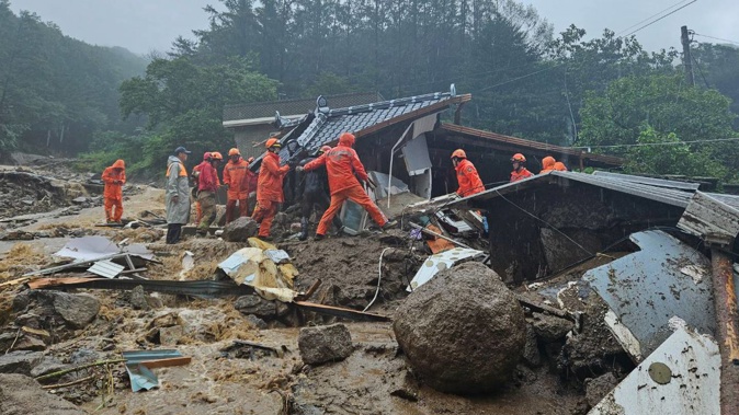 Rescue workers search for people in houses collapsed following a landslide in Yecheon, South Korea. Photo / AP