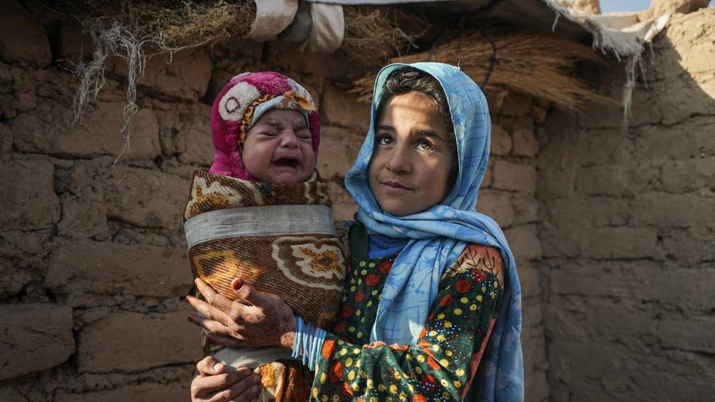 Qandi Gul holds her brother outside their home housing those displaced by war and drought near Herat, Afghanistan. Photo / AP