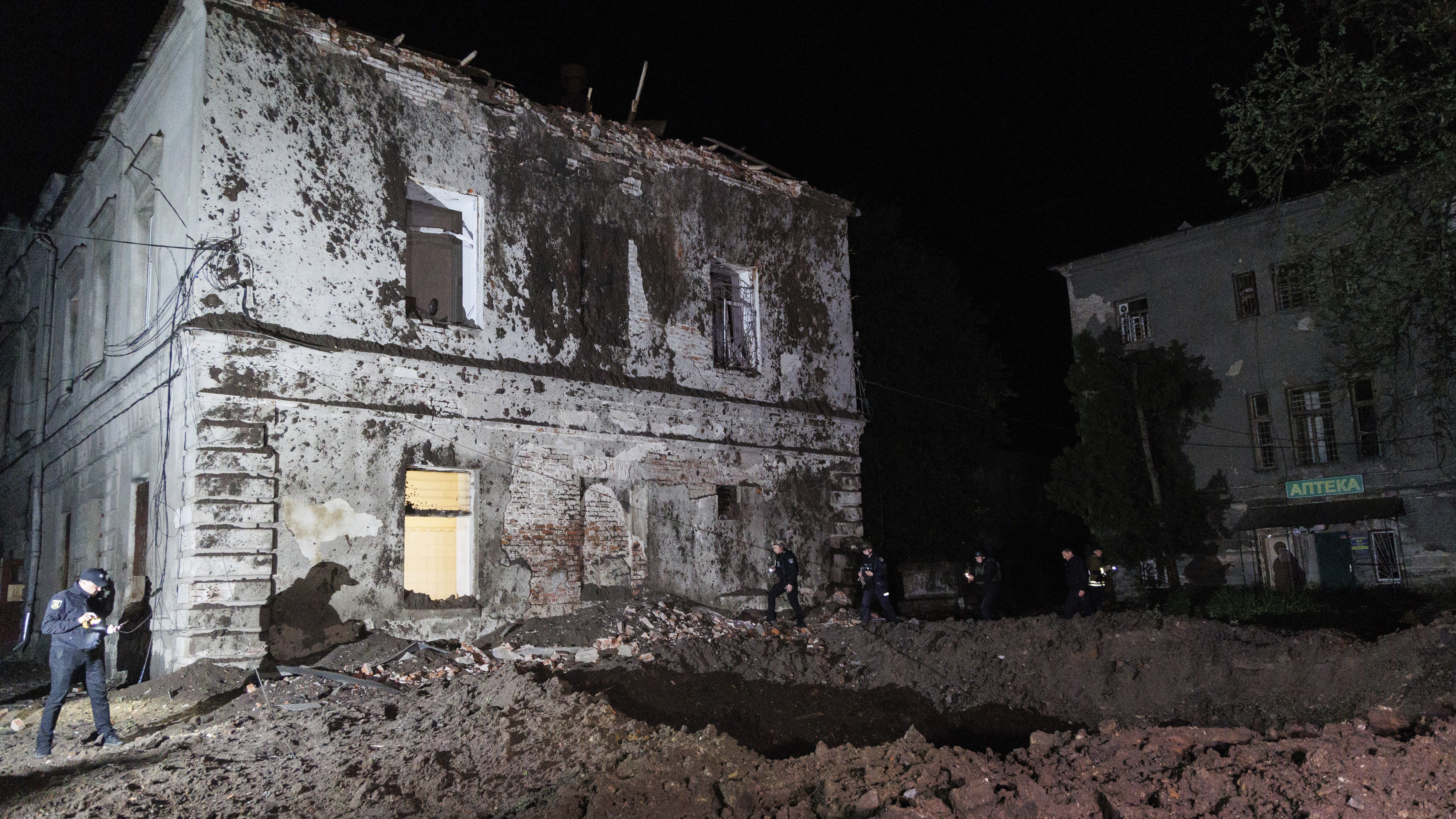 Police offices walk in front of a crater after a Russian rocket attack on mental hospital №3 in Kharkiv, Ukraine, Saturday, April 27, 2024. (AP Photo/Yakiv Liashenko)