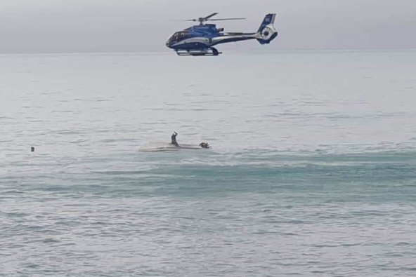 A rescue helicopter circling the upturned boat in Goose Bay, Kaikoura, yesterday. Photo / Supplied