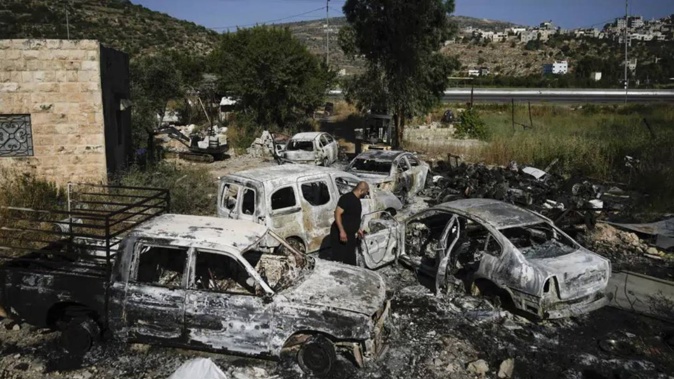 A Palestinian man inspects scorched cars, including some junked for spare parts, in the West Bank village of A Laban al-Sharkiyeh. Photo / AP