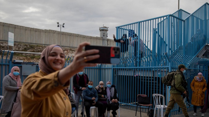Palestinians take a selfie after receiving the coronavirus vaccine from an Israeli medical team at the Qalandia checkpoint between the West Bank city of Ramallah and Jerusalem. (Photo / AP)