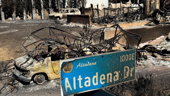 An overhead pole camera image shows wildfire damage to an Altadena Drive street sign and home destroyed by the Eaton Fire in Altadena, Los Angeles County, California on January 14, 2025. Powerful winds on January 14 threatened to rekindle and whip up major fires that have devastated parts of Los Angeles, killing at last 24 people and changing the face of America's second biggest city -- perhaps forever. (Photo by Patrick T. Fallon / AFP)