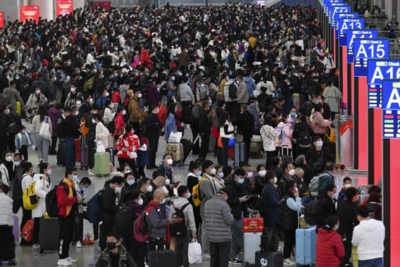 In this photo released by Xinhua News Agency, People wearing face masks with their luggage prepare to catch their trains at the North Railway Station in Shenzhen in south China's Guangdong province, Saturday, Jan. 7, 2023.