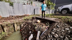 Harish Lodhia inspects a blocked culvert in the creek below his Stoddard Rd property in Mt Roskill where debris has built up along the metal grill designed to stop large items from flowing into the pipe. Photo / Dean Purcell
