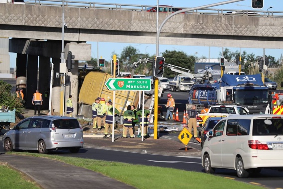 A container truck has rolled, spilling tonnes of carpet glue across State Highway 20 in Auckland. Photo / Michael Craig