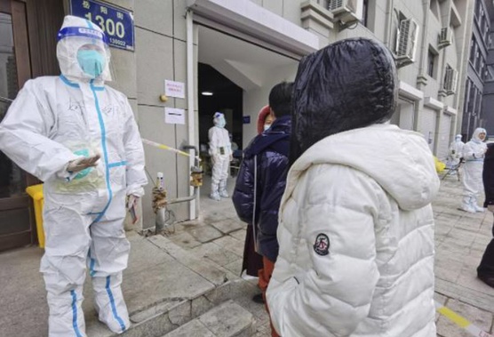 A worker wearing a protective suit speaks to residents in a neighbourhood in Changchun in northeastern China's Jilin Province. (Photo / AP)