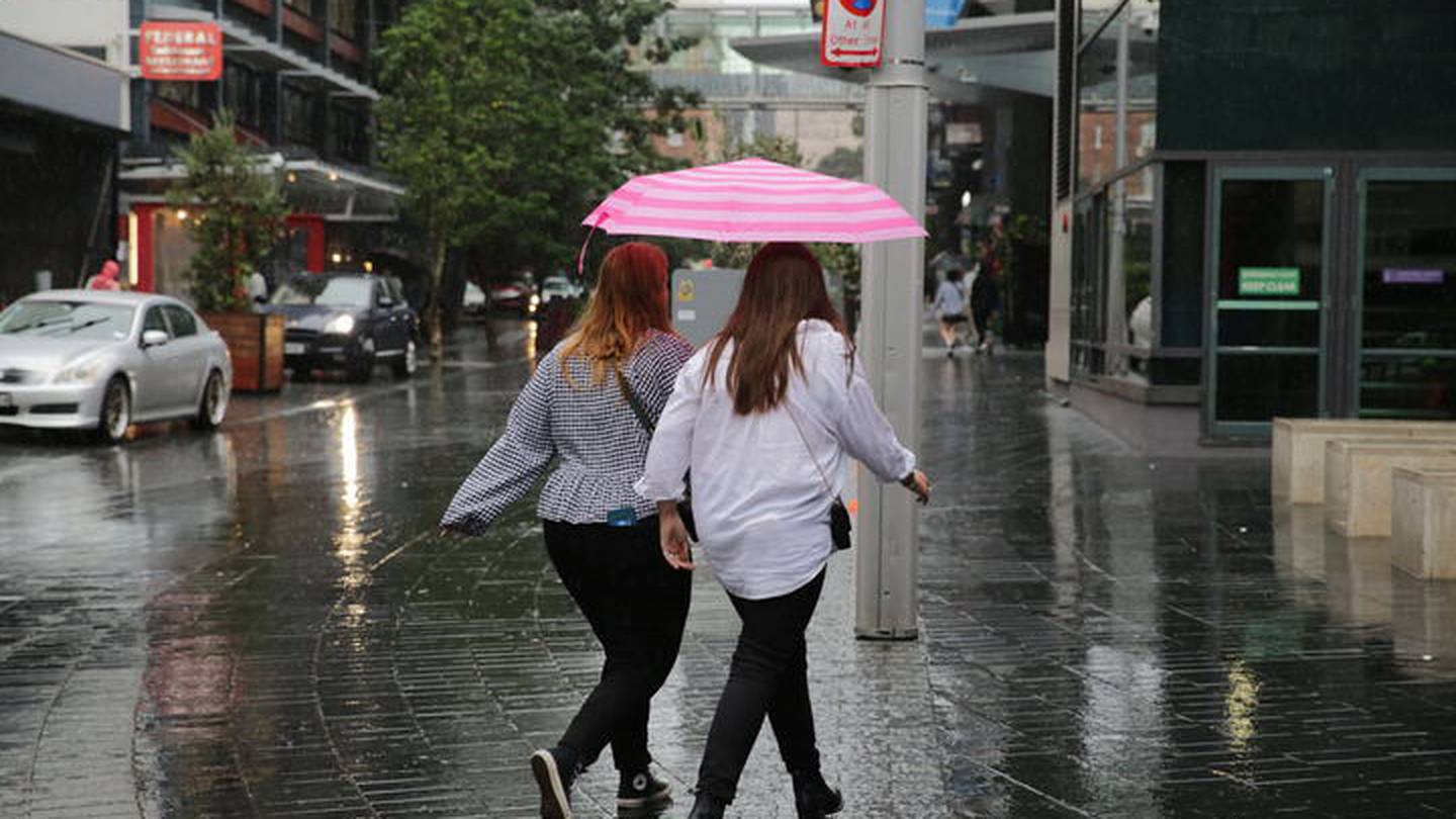 Two women shelter under an umbrella amid heavy rain in Auckland. Photo / Sylvie Whinray