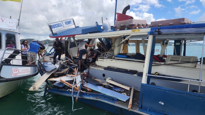 Passengers on the stricken Blue Ferry clamber over wreckage to the safety of the Happy Ferry while others tend to the injured skipper. Photo / Elliot Bexon