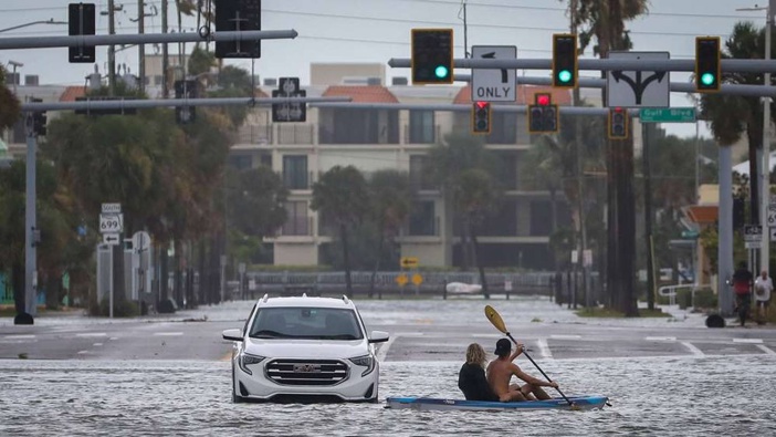 People kayak past an abandoned vehicle in the intersection of Boca Ciega Drive and Pasadena Avenue in St. Pete Beach, Florida. Photo / Chris Urso / Tampa Bay Times via AP