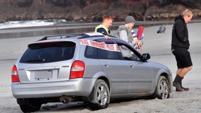Police tape covers a stolen car which was abandoned on Tomahawk Beach, in Dunedin. Photo / Stephen Jaquiery