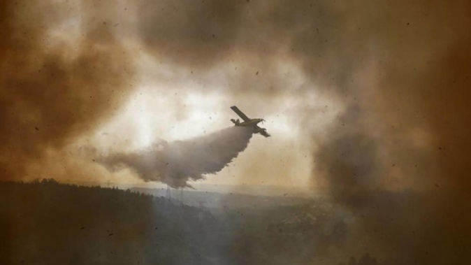 A firefighting airplane drops its load on a forest fire raging in the village of Casal da Quinta, outside Leiria, central Portugal. Photo / AP