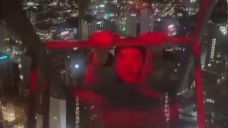 A young man is seen climbing a crane tower on the 54-level Seascape building in downtown Auckland.