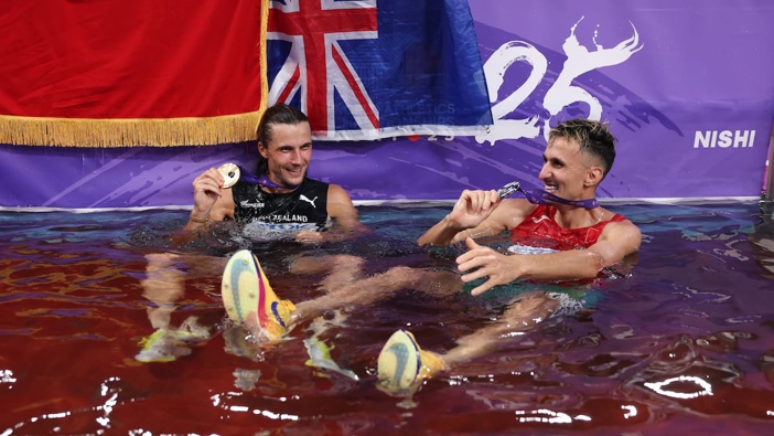 Gold medalist Geordie Beamish of New Zealand and silver medalist Soufiane El Bakkali of Morocco celebrate with their medals inside a water jump pool following the Men's 3000 Metres Steeplechase final. Photo / Getty Images
